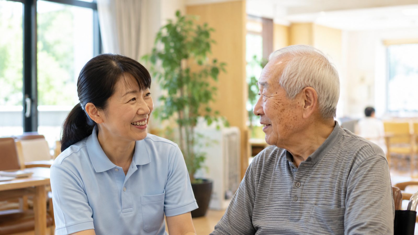 明るい施設で会話する介護スタッフと高齢者